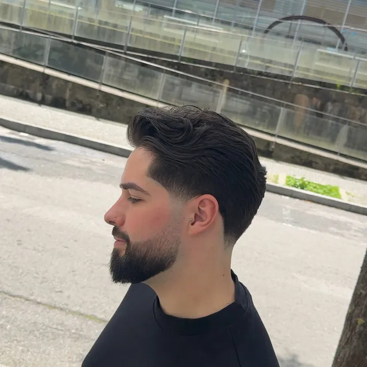Cabelo penteado para trás com degradê e barba aparada