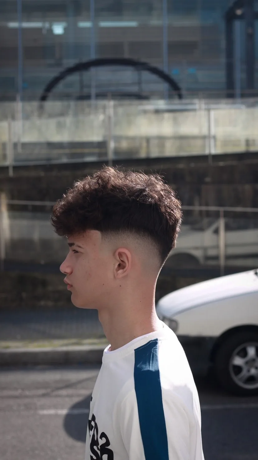 Corte com caracóis no topo e degradê, de perfil