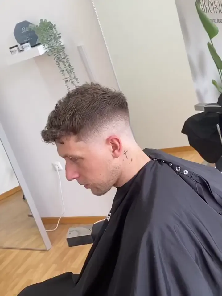 Corte com caracóis curtos e degradê, de perfil, no salão